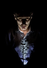 Stylish dark portrait of adult caucasian man who seems like maniac or psycho. Isolated on black background. Low-key lighting.