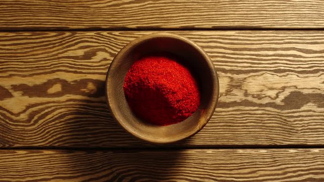 TOP VIEW: Portions of ground red pepper appear in a wooden cup - Stop motion