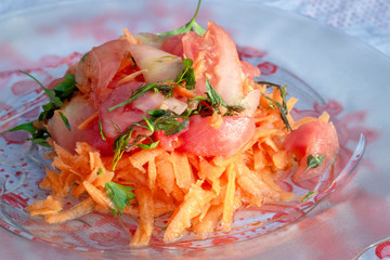Close shoot of carrot and tomato mix oil dropped salad on transparent plate