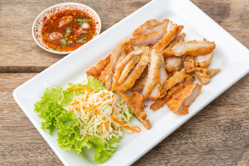 Fried Streaky Pork, vegetable and sauce (Thai food) in the white dish put on the wooden table.