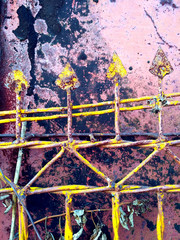 Old damaged metal wall surface with rusty yellow spike fence