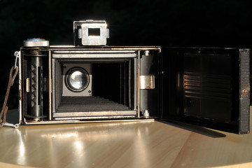 Old folding camera with an open back cover, internal view of the lens, camera bellows and spool for...