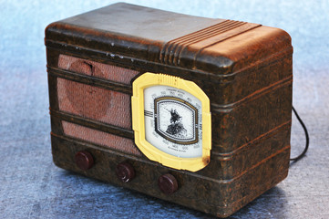 The scale is written in Cyrillic "Middle Waves" and "Long Waves». Old tube radio receiver in a brown metal case painted with hammered enamel, white adjustment scale and three knobs on the front panel