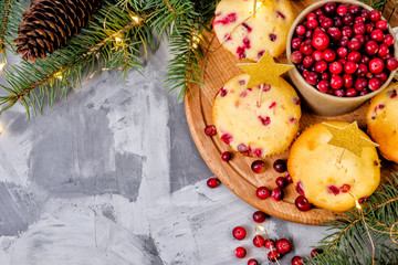 Cranberry cupcakes with a golden star topper lie on a wooden tray