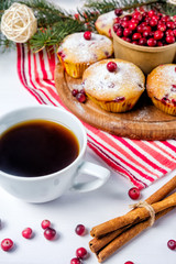 Cranberry cupcakes sprinkled with powdered sugar on a wooden tray. next is a white cup with tea (coffee, chicory)