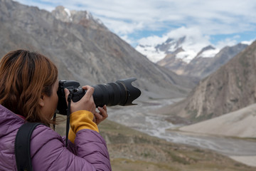 Travelling woman with camera on rang of mountains with snow.