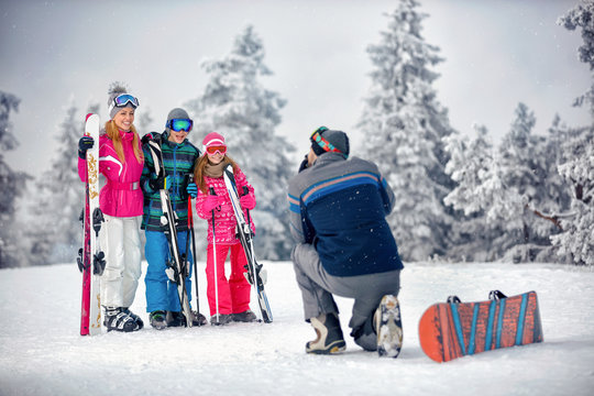winter season - father take photographing family on vacation in snow mountains