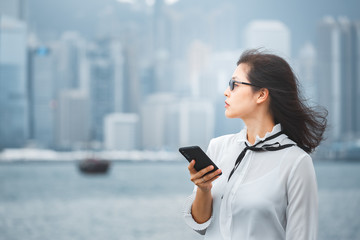 Successful business woman using smartphone in city