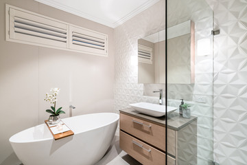 Fototapeta na wymiar Large modern bathroom interior with floor to ceiling tiling and luxury fittings.