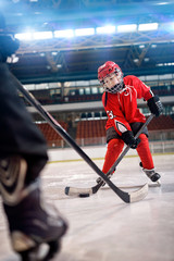 Plakat boy play ice hockey in action kicking on goal.