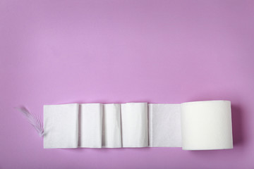 Roll of toilet paper and feather on color background, top view. Space for text