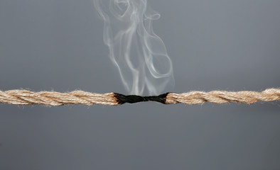 Rope burnt to breaking point on dark background