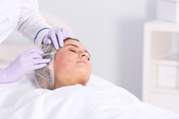 Obraz na płótnie Canvas Woman undergoing face biorevitalization procedure in salon. Cosmetic treatment