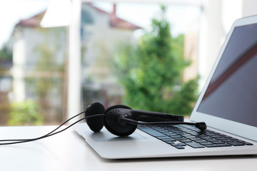 Modern laptop and headset on table indoors. Technical support concept