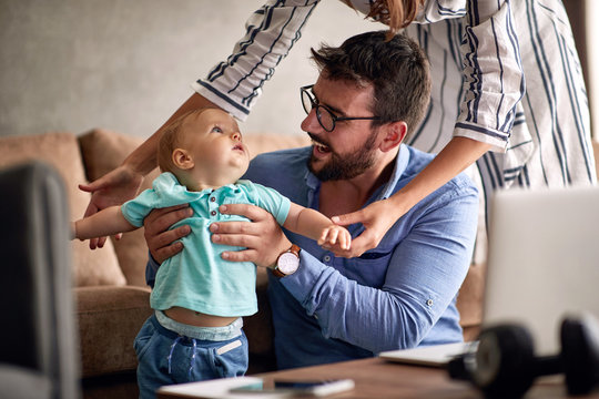 Happy Family - Father Using A Laptop Computer For Work At Home While Looking After His Baby Son.