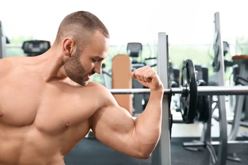 Fototapeta na wymiar Shirtless strong young man posing in gym