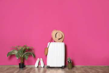 Large suitcase for travelling and beach items near color wall
