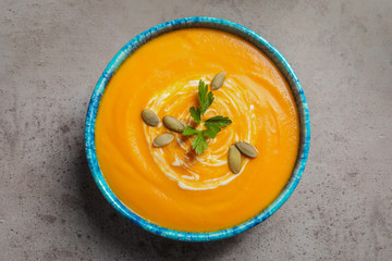 Bowl with tasty pumpkin soup on gray table, top view