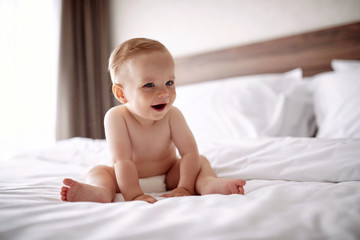 Beautiful smiling boy in white bedroom. child relaxing in bed..