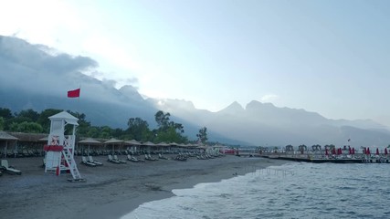 Sunset on the beach. Typical turkish hotel with sun loungers and wooden pontoon. Kemer, Turkey.
