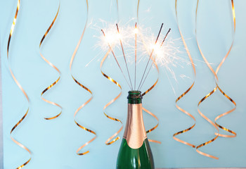 Creative composition with bottle of champagne and sparklers on color background