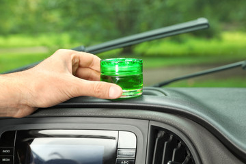 Man putting air freshener on dashboard in car, closeup