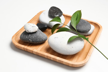 Plate with spa stones on white background