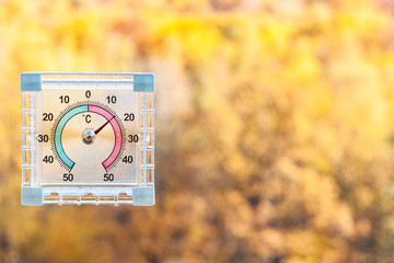 thermometer on window and blurred yellow woods