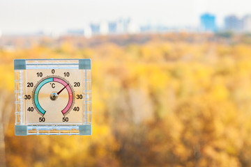 thermometer on window and blurred yellow city park