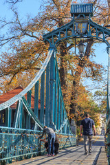 Opole - a penny bridge (most groszowy) on miller channel (kanał młynówka). Two lovers pinning their commemorative padlock to the balustrade - obrazy, fototapety, plakaty