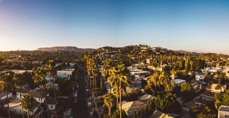 Beverly Hills street with palm trees at sunset in Los Angeles with Hollywood sign on the horizon.