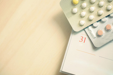 Contraceptive control pills on date of calendar background on the table wood. health care and medicine concept	