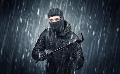 Burglar in action in black clothes with rainy concept. 