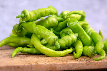 Capsicum annuum sweet chilli peppers, group of green fruits on wooden cutting board
