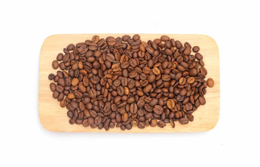 Many coffee beans are brown and have a pleasant aroma, on a wooden plate.