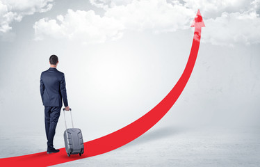 Young businessman with back leaving on the red arrow carpet to the skies with luggage on his hand
