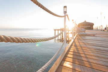 wooden pier sun-drenched, sunset or dawn, the silhouette of a man on a writing in the rays of the sun