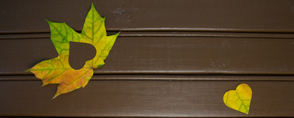 Autumn red and orange leaves with heart. Fall wooden background.