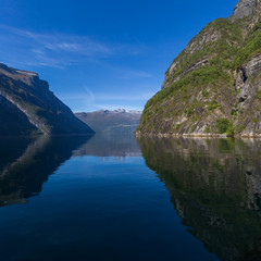 mountains reflected in Geiranger fjord, blue sea, sky
