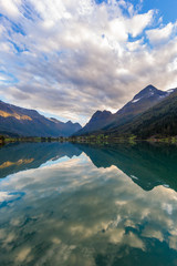 mountains mirrored in Geiranger fjord, clouds
