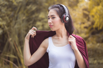 Young beautiful woman running in autumn park and listening to music with headphones.