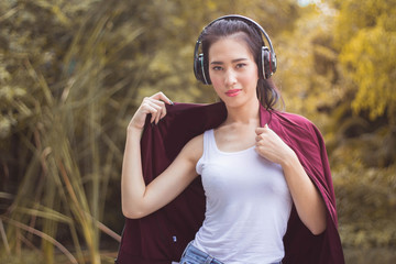 Young beautiful woman running in autumn park and listening to music with headphones.