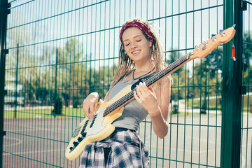 Positive woman smiling and playing the guitar outdoors