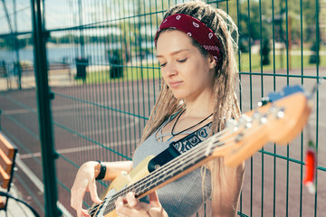 Peaceful musician leaning on the chain link fence and playing the guitar