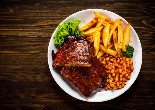 Tasty grilled ribs with french fries and vegetables