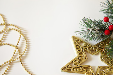 Fir tree branches, red berries, golden decorations on white background. Christmas backdrop.