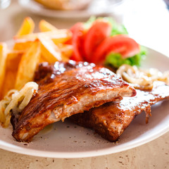 Tasty grilled ribs with french fries and vegetables