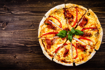 Pizza with ham and pepper on wooden table
