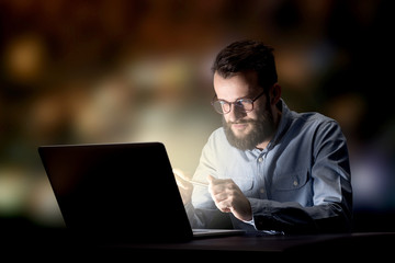 Young handsome businessman working late at night in the office