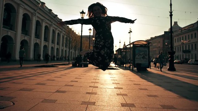 Happy cute girl having fun outdoor at city streets urban background. Beauty woman spinning, jumping and laughing. Freedom. Extreme Slow motion 180 fps. Wide shot